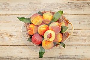 Peaches in a basket on a wooden background with a slice of sliced juicy peach with a stone