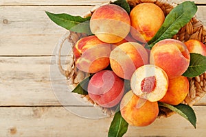 Peaches in a basket on a wooden background with a slice of sliced juicy peach with a stone.