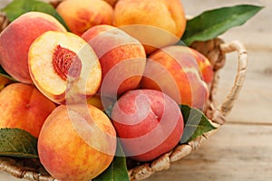 Peaches in a basket on a wooden background with a slice of sliced juicy peach with a stone