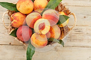 Peaches in a basket on a wooden background with a slice of sliced juicy peach with a stone.