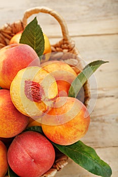 Peaches in a basket on a wooden background with a slice of sliced juicy peach with a stone. photo