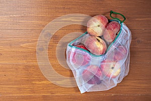 Peaches in ecological packaging. Reusable bags for vegetables and fruits. Shopping in the store, retail. Eco friendly packaging of