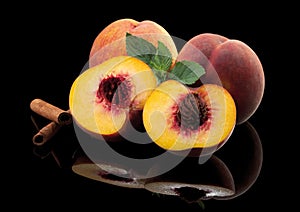 Peaches, whole and cut on a black mirror background