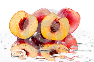 Peaches whole and cutted into two halves in water drops on white background isolated close up