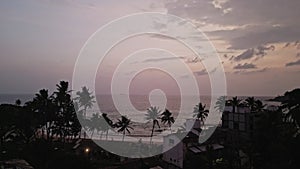 Peacock perches atop red-tiled roof overseeing vast ocean. Bird fans vibrant tail, coastal community backdrop, tropical