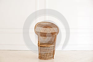 Peacock wicker chair in a spacious bedroom interior. Rattan peacock armchair by the white empty wall in the living room. Scandinav