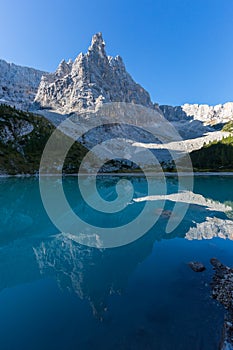 Peak of Dito di Dio mountain reflected in green water of lake Sorapis