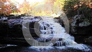 Peak fall foliage surrounds beautiful cascading lower Shohola Falls