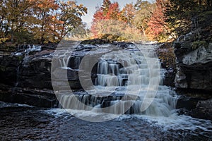 Peak fall foliage surrounds beautiful cascading lower Shohola Falls