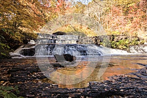 Peak fall foliage surrounds beautiful cascading middle Shohola Falls