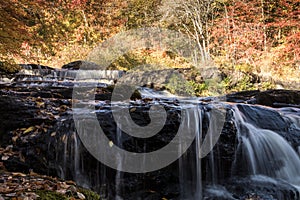 Peak fall foliage surrounds beautiful cascading middle Shohola Falls