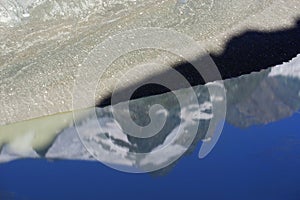 The peak of Grossglockner mountain is reflected in the water collected from the melting Pasterze glacier.