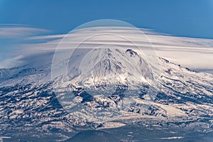 The peak of Mount Shasta is covered by lenticular clouds in California, USA