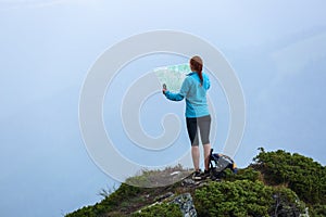 On the peak of the mountain the touris girl with the map and compass is searching for the way to dream. The horizon in the fog. photo