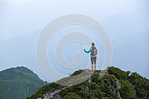 On the peak of the mountain the touris girl with the map and compass is searching for the way to dream. The horizon in the fog. photo