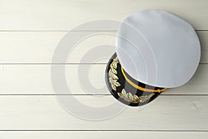 Peaked cap with accessories on white wooden background, top view. Space for text