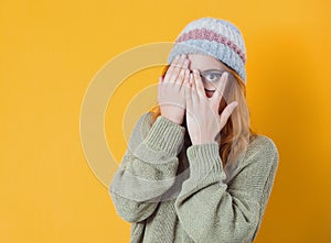 Peaking. Obscured face. Close up young woman covering face with hands. Shame, isolated on yellow background. Ashamed girl