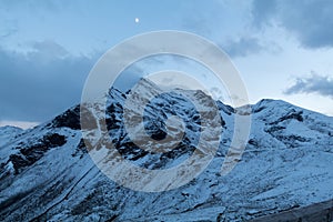 Peaks of Austrian alps and a moon in summer