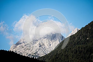 peaks of the wetterstein mountains in the clouds in the early morning, view from mittenwald town