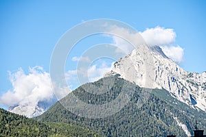 peaks of the wetterstein mountains in the clouds in the early morning, view from mittenwald town