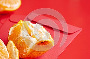 Peal Mandarin oranges on top of Chinese New Year red packet. Chinese New Year celebration concept