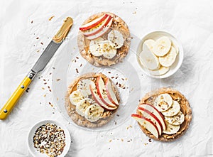 Peanut butter, apple, banana, flax and chia seed crackers toast on a light background