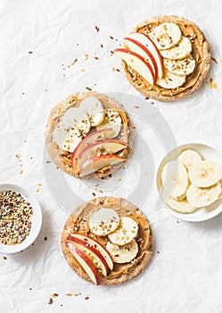 Peanut butter, apple, banana, flax and chia seed crackers toast on a light background