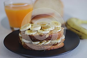 Peanut butter banana honey toast sandwich served with Orange juice, an easy breakfast idea