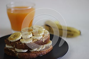 Peanut butter banana honey toast sandwich served with Orange juice, an easy breakfast idea