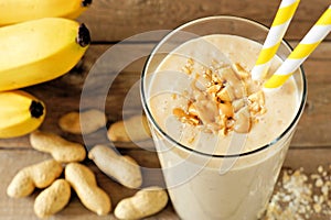 Peanut-butter banana oat smoothie on rustic wood with scattered ingredients