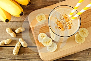 Peanut-butter banana oat smoothie with straws, on wood