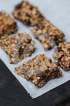 peanut butter chocolate chip granola bars with oats on white parchment paper with neutral background