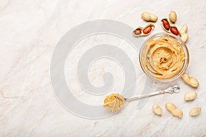Peanut butter in glass plate with peanuts in shell, peeled peanuts, vintage spoon with peanut butter. Creamy peanut paste flat lay