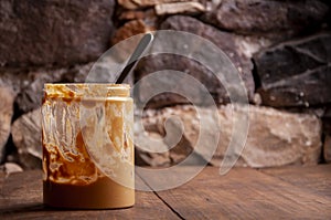 Peanut butter inside jar nd spoon with stone background