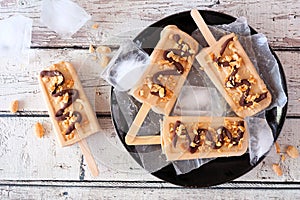 Peanut butter popsicles on a black plate, table scene