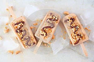 Peanut butter popsicles on a white marble background