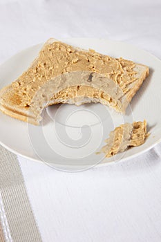 Peanut butter on slice of bitten bread