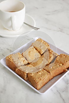 peanut butter spread on brown bread and cup of tea on table