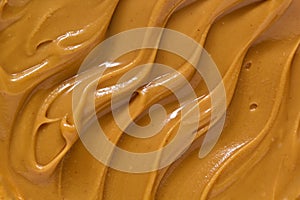 Peanut butter texture background. Brown nut paste smear closeup