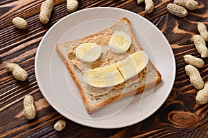 Peanut butter toast with banana slices on wooden background