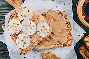 Peanut butter toast with banana slices on wooden background