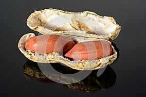 Peanut on glossy black surface with reflection. peanut with two kernels with open shell macro close-up, high resolution full depth