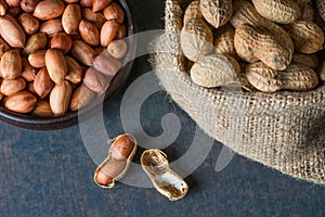 Peanut in nutshell in burlap sack or sackcloth on wooden background. Composition of peanuts