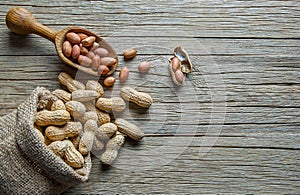 Peanut in nutshell in burlap sack or sackcloth on wooden background. Composition of peanuts