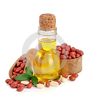 Peanut oil in a glass bottle with peanuts in bowl