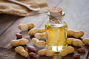 Peanut oil in glass bottle and peanuts on wooden table