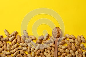 Peanut and spoon with peanut butter on yellow background