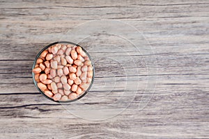 Peanuts in a bowl wood table. The peanut also known as the groundnut  or goober or monkey nut is a legume crop grown mainly for it