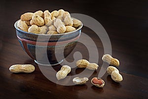 Peanuts in a ceramic bowl on a dark brown table, copyspace