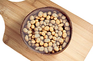 Peanuts in glaze shell in a round plate on a cutting board isolated